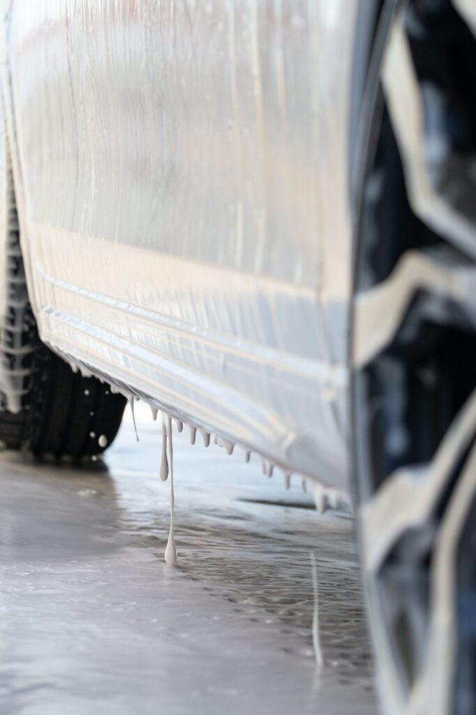 Close up of car is covered with foam at self-service car wash. Bottom view.